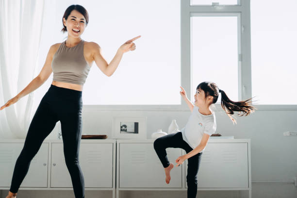 alegre joven madre asiática y niña pequeña divirtiéndose bailando juntos mientras hacen ejercicio en casa - togetherness learning playful mother fotografías e imágenes de stock