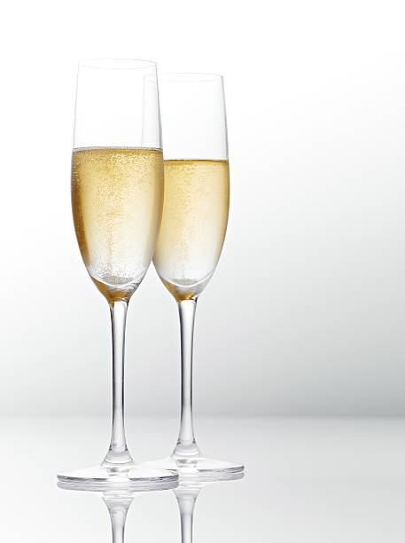 Two hall full tall glasses of champagne on white surface stock photo
