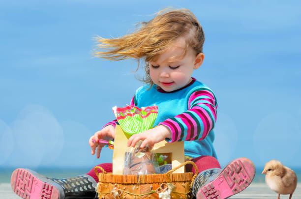 Little girl in a blue dress sitting in a wicker basket.