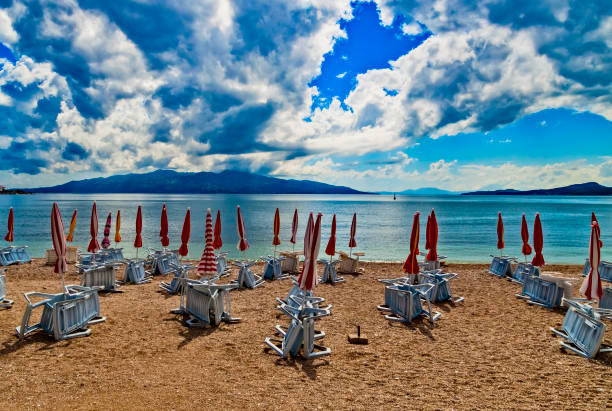 plage vide avec parasols rouges de plage fermé. beau ciel nuageux. plage sans voyageurs et touristes. annulations dues au coronavirus covid-19. quarantaine. - beach cancelled close up color image photos et images de collection