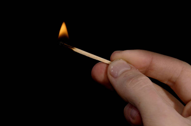 istock burning match in hand on black background 1223950906