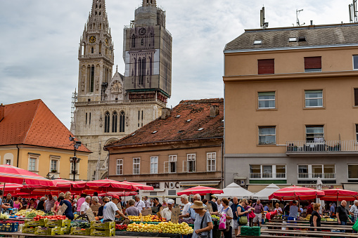 Zagreb, Croatia. 11th Aug, 2019. Locals and tourists buying groceries at the popular Dolac market with the towers of Zagreb Cathedral in the background