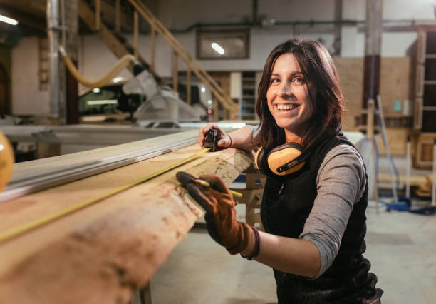 mujer sonriendo y midiendo tablero de madera en un woorkshop de carpintería - carpintero fotografías e imágenes de stock