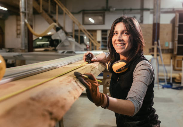 mulher sorrindo e medindo tábua de madeira em uma marcenaria woorkshop - artesão - fotografias e filmes do acervo