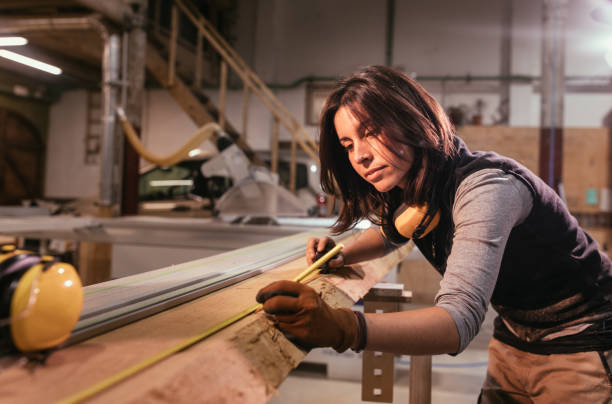 istock Woman measuring wooden board in a carpentry workshop 1223955357