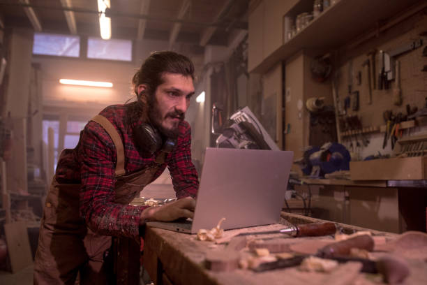 istock Man in carpentry workshop typing on laptop 1223956225