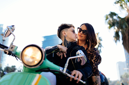 Alternative hipster lesbian couple on a motorcycle together in city streets
