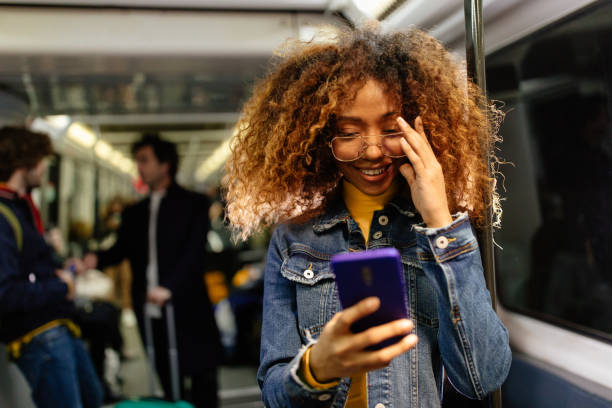 istock Young black woman, afro hairstyle using smartphone on train 1223958514