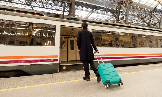 Businessman on train station in Spain with trolley luggage in his hand