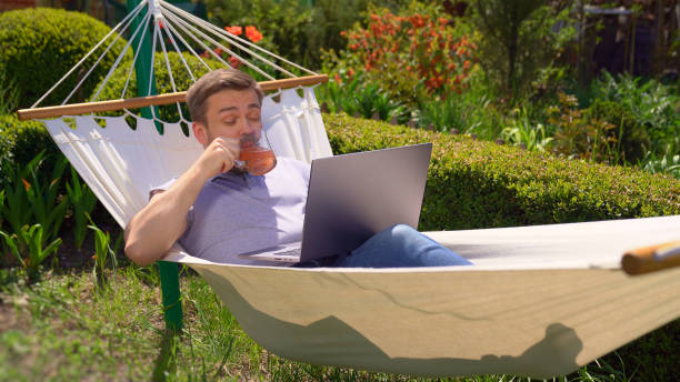 istock man lies in hammock, work on computer drink juice. 1223959057
