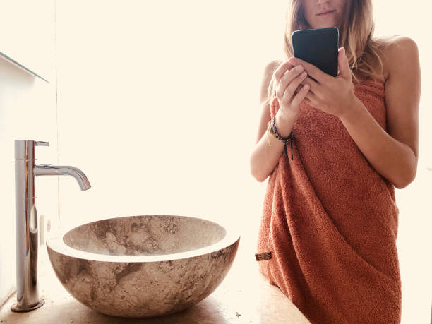 istock Young woman in the bathroom using modern smartphone. 1223962700