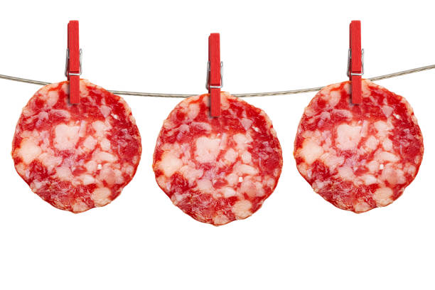 Slices of salami are hanging on a rope photographed on white background