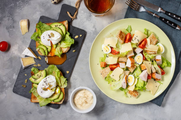 istock Fresh Caesar salad with poached eggs and avocado on toast on concrete background. Healthy and diet food concept. 1223963197