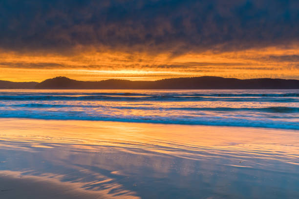 istock Cloud Covered Sunrise Seascape and large rock on beach 1223964476
