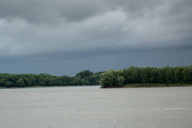 Thunderclouds over the Danube river in the spring. The strong wind and clouds pass on the river. Dark dramatic rain clouds over countryside landscape in Braila,  Romania; outdoors