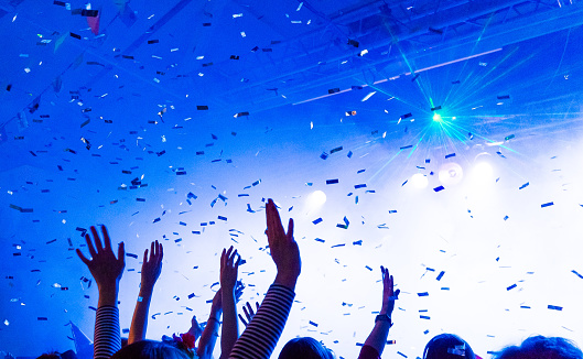 Hands in the air with flying confetti at a prom party