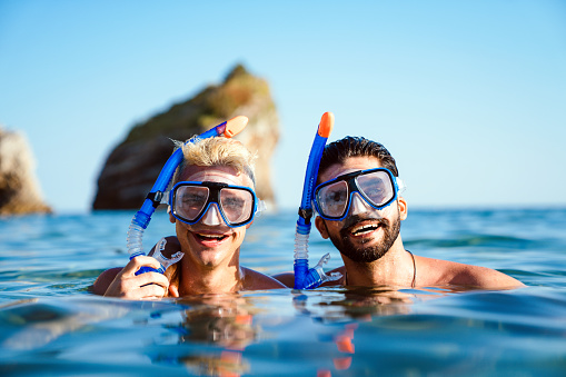 Happy friends men enjoying summer vacation and scuba diving on the sea