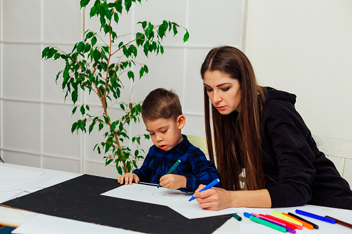 female teacher teaches a little boy to draw
