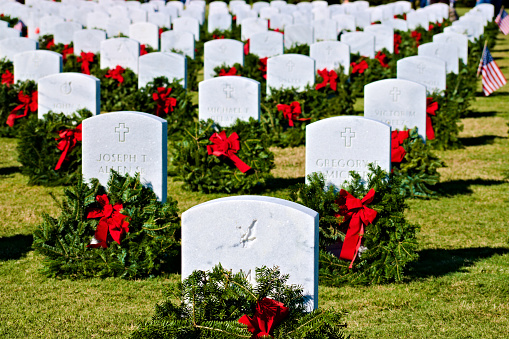 Landscape. The rows of veterans' headstones Arranged with award evergreen wreathes and American flags. Created in Cape Canaveral, FL, 12/14/2019