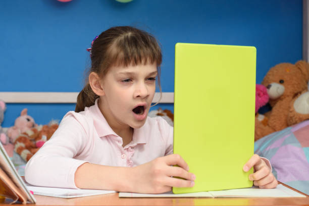 istock Girl at home at the table yawns while watching a boring video tutorial 1223980454