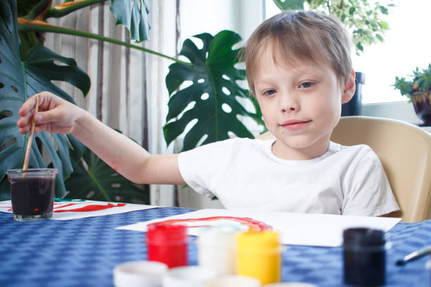 istock Happy cheerful child drawing with brush, in home interior during coronavirus self-isolation and quarantine. Creativity concept 1223980484