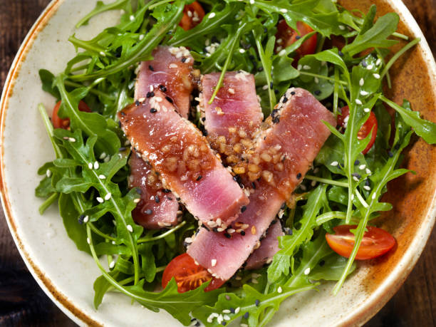 semi di sesamo in crosta di tonno ahi scottato e insalata di rucola con zenzero all'aglio e condimento di soia - tuna steak grilled tuna food foto e immagini stock