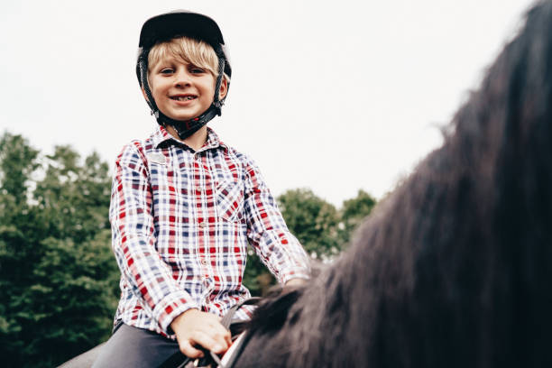 istock Smiling boy riding on his black horse 1223981914