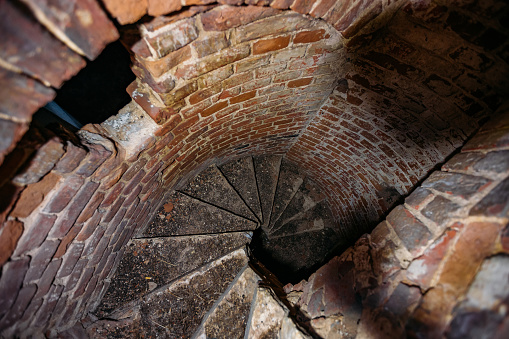 Old spiral staircase inside red brick tower, upside view.