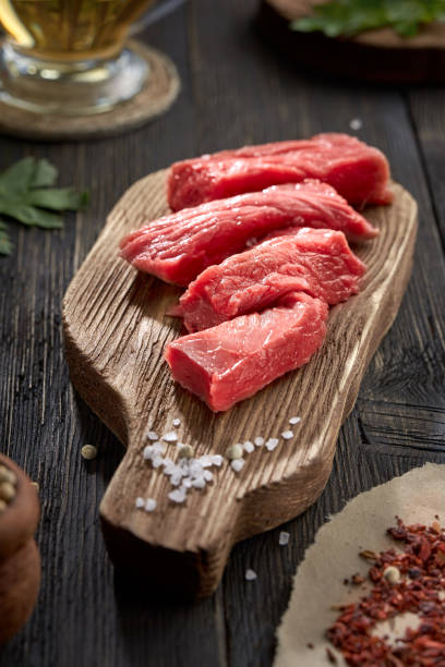 istock Sliced fresh raw beef and coarse salt on an old chopping Board. 1223985629
