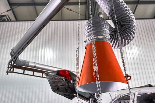 Hood of an industrial air extractor. A closeup and low angle view on the mouthpiece of a dust extraction system inside a workshop.