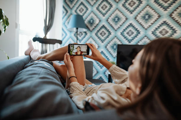 istock Young woman lying on couch and making video call with girlfriend 1223987594