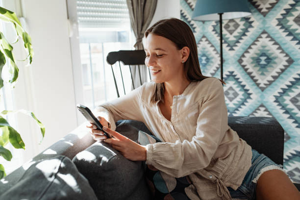 istock Casual young woman using mobile phone at home during quarantine 1223987989