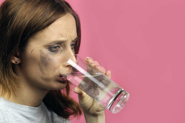 istock crying girl drinks water on a pink background 1223989173