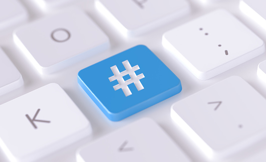 Hashtag symbol written on a blue button of a computer keyboard. Horizontal composition with selective focus and copy space. High angle view. Horizontal composition with copy space. Social media concept.