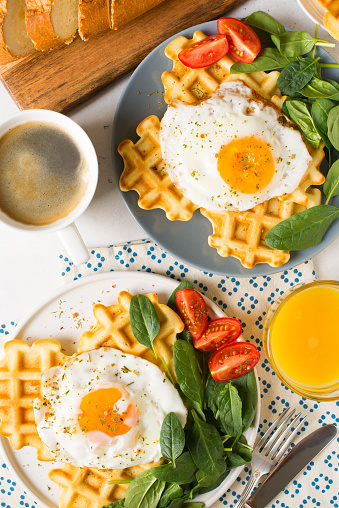 Fried egg, spinach, waffles and cup of coffee espresso for two person on white background, flat lay, top view, copy space