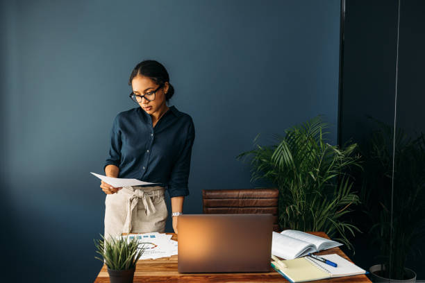 istock Young woman working from home standing at a desk and looking on documents 1223995543