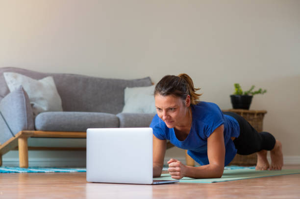 istock Young girl doing online exercise session at home doing a plank 1223996040