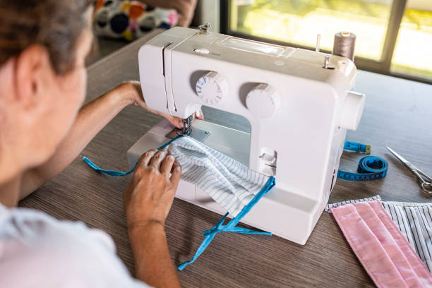 istock Woman making face masks with a sewing machine at home 1223996900