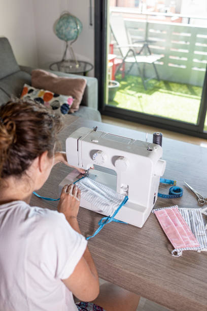 istock Woman making face masks with a sewing machine at home 1223996903