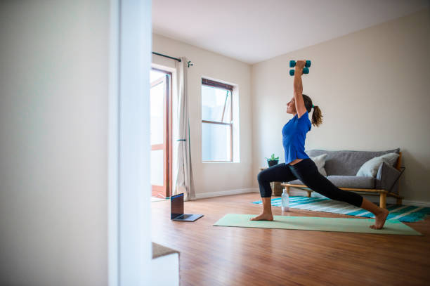 giovane ragazza che fa sessione di esercizio online a casa con manubri che alzano lo stato - yoga meeting foto e immagini stock