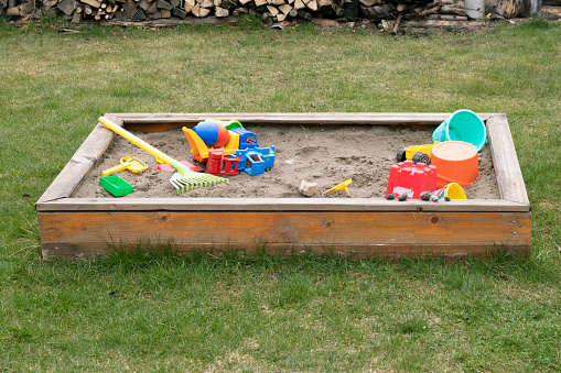 children's sandbox with toys on green grass