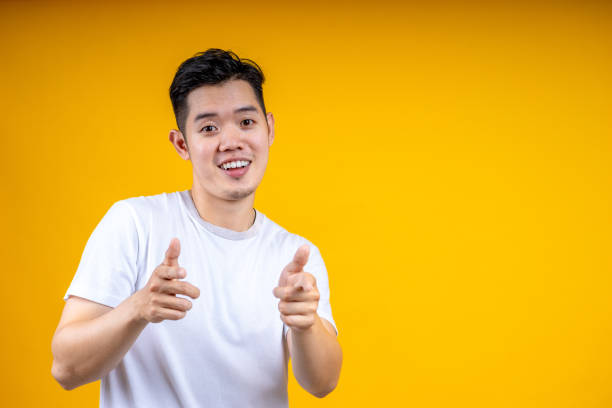 istock Young handsome Asian man with beard over isolated yellow background points finger at you while smiling 1224001305