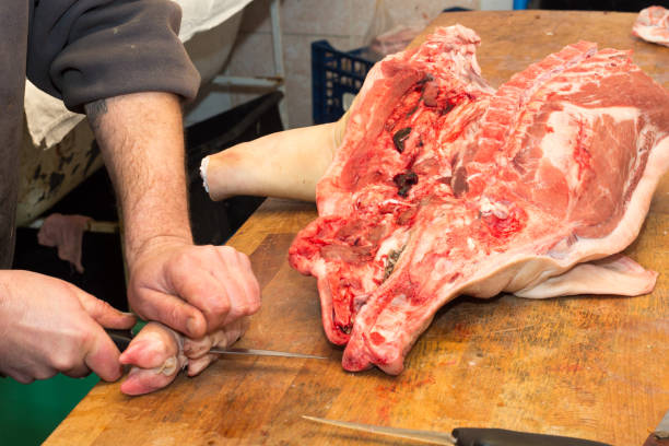 Butcher cutting raw pork meat.
