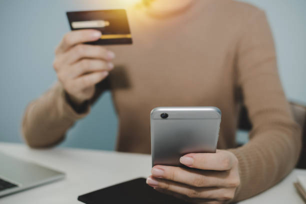 istock young woman entering security code with mobile phone and paying with mock up credit card and laptop computer on desk at home office, shopping online, electronic pay and digital technology concept 1224004222