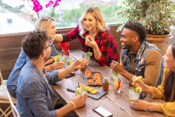 grupo multirracial de jovens amigos millennials conversando e jantando juntos - estudantes festejam no rooftop café - home interior cocktail bar women - fotografias e filmes do acervo