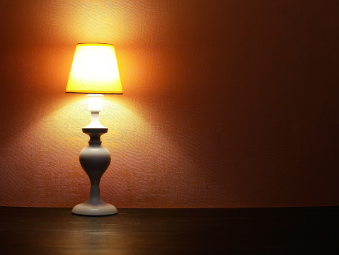 Elegance white desk lamp with yellow lampshade against red wall