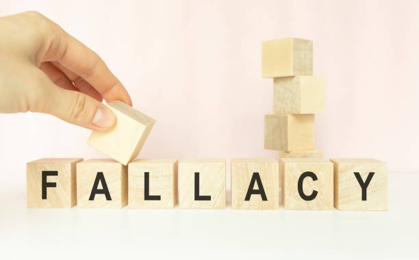 istock FALLACY word on cubes on a light table with a flower and a light background 1224009255