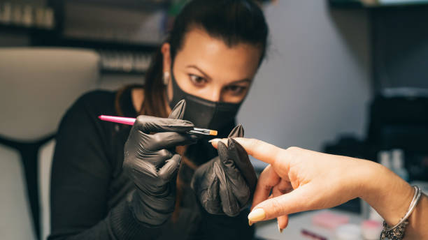 manicuristi che applicano il processo di lucidatura del gel. procedura del salone. il maestro rivesti le unghie del cliente con una vernice. - nail salon fingernail manicure design foto e immagini stock