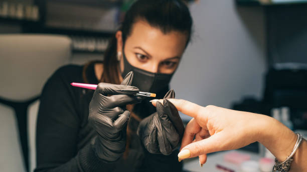 маникуристы применяют гель польский процесс. процедура салона. мастер покрывает ногти клиента лаком. - nail salon fingernail manicure design стоковые фото и изображения