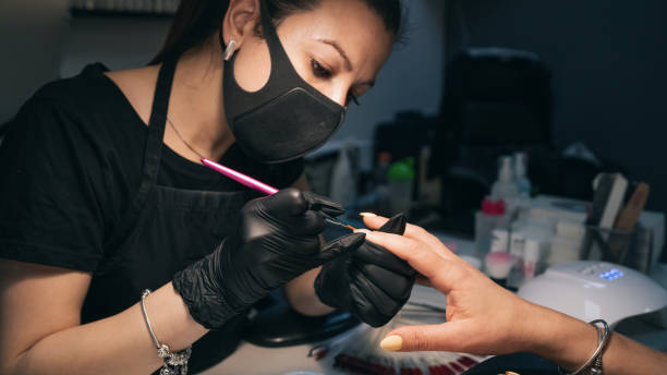 istock Manicurists applying gel polish process. Salon procedure. The master coats the client's nails with a varnish. 1224010844